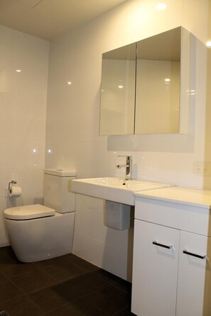 Un baño moderno con inodoro, lavamanos y espejo.
