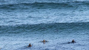 A view of the ocean with three individuals in the water.