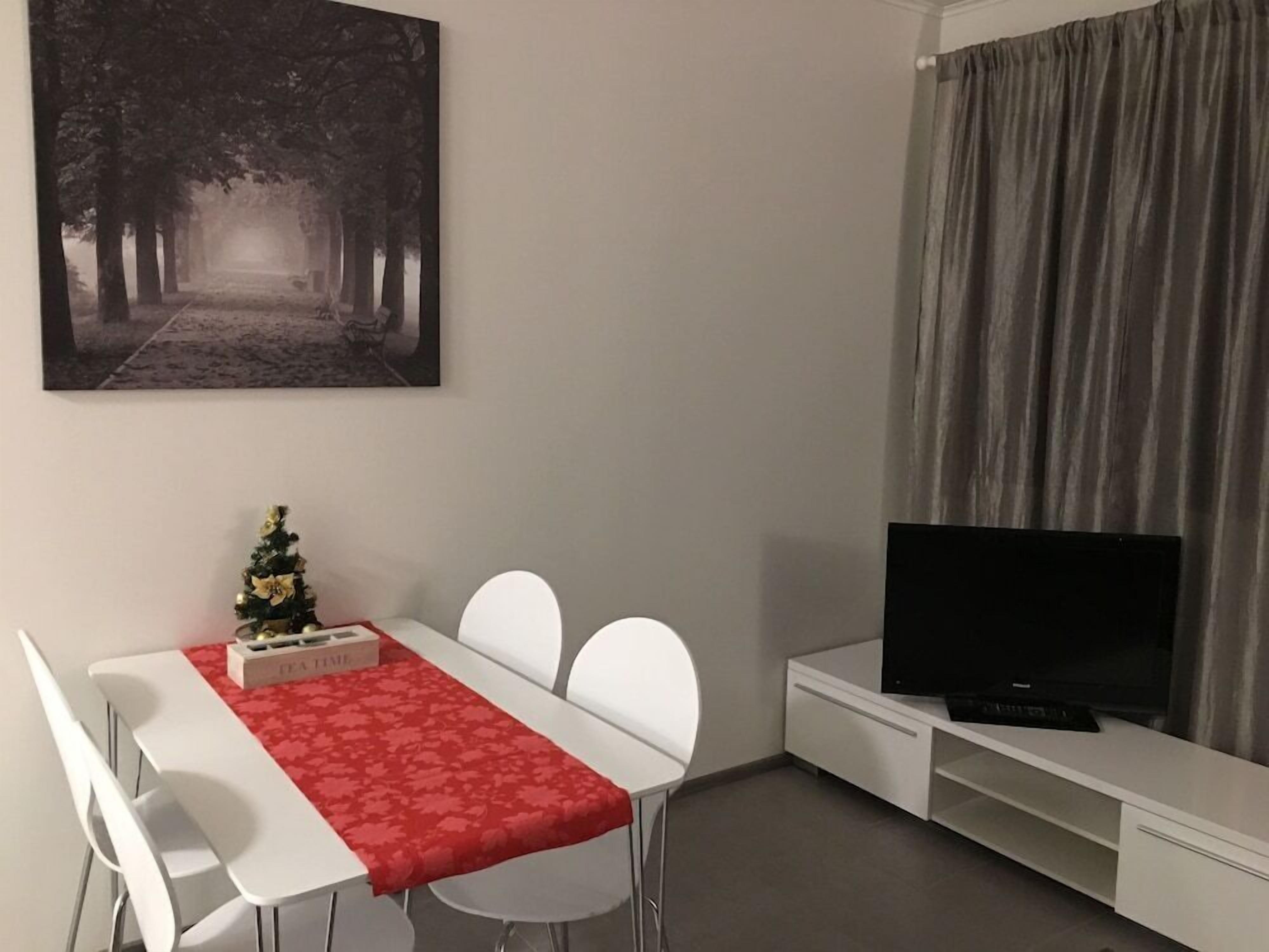 A modern living room with a dining area, a flat-screen TV, and a Christmas tree.