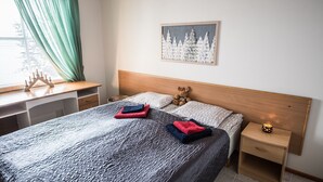 A neatly arranged bedroom with a bed, bedside tables, a desk, and a window with curtains. - Arctic Resort Delight (Rovaniemi)
