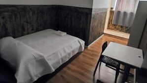 A small, compact room with a bed, a table, and a chair.