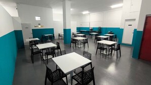 A conference room with multiple tables and chairs, white walls, and teal accents.