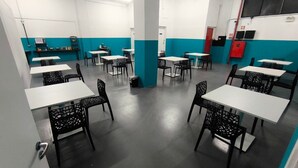 A dining area with tables and chairs, a counter with a display, and a red door.