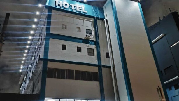 A hotel building with a prominent 'HOTEL' sign at the top, multiple floors, and a modern architectural design.
