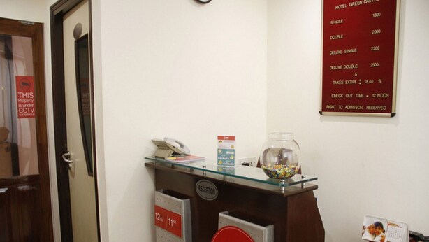 Una recepción con encimera de vidrio, teléfono y pecera. Se ve un cartel que dice 'OYP ROOMS' y un letrero en la pared con los precios de las habitaciones.