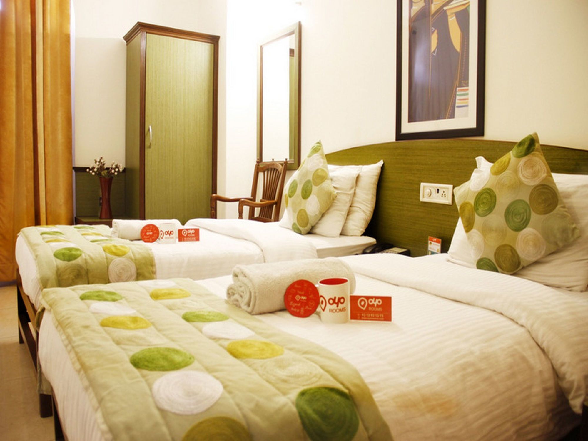 A hotel room with two beds, each with a green and white polka dot bedspread, a wooden headboard, and a green door.