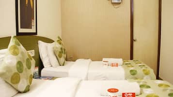 A hotel room with two beds, a wall-mounted heater, and a door.