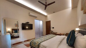 Una habitación de hotel con una cama, televisor, ventilador de techo y armario.