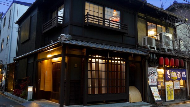 A traditional Japanese building with a wooden facade, a tiled roof, and a small balcony. - Machiya Kaemon Kyoto sta (Kyoto)