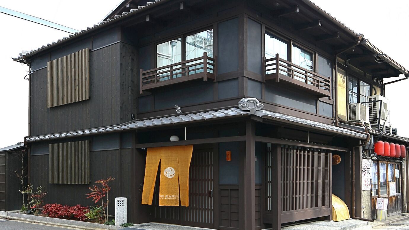Un bâtiment traditionnel japonais, caractérisé par une façade sombre, de nombreuses fenêtres et un balcon en bois.
