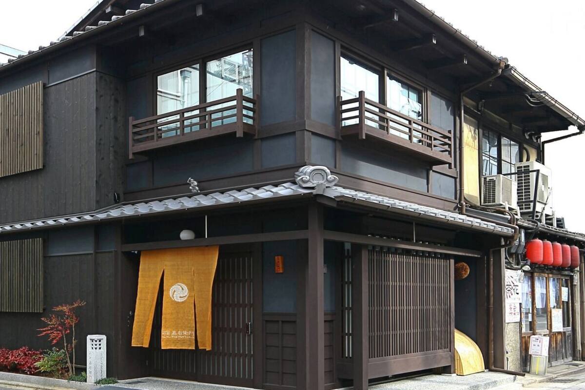 Un bâtiment traditionnel japonais, caractérisé par une façade sombre, de nombreuses fenêtres et un balcon en bois.