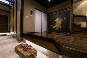 Una habitación japonesa tradicional con suelo de tatami, un banco de madera bajo, una puerta corredera y un biombo decorativo con motivo de león.