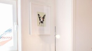 Una habitación con un radiador, un cuadro en la pared, una lámpara de pie y una silla.