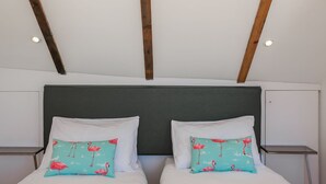 Una cama doble con almohadas a juego, un cabecero oscuro y vigas de madera en el techo.