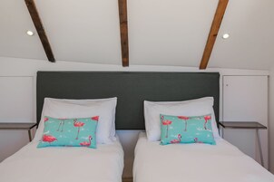 Una cama doble con almohadas a juego, un cabecero oscuro y vigas de madera en el techo.