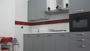 A modern kitchen with grey cabinets, a black oven, and a red accent wall. - Mary''s Sweet Home Appartamento Napoli (Naples)