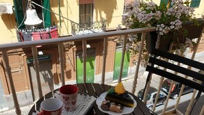 A balcony with a table set with a red mug, a plate of pastries, and a green dessert. - Mary''s Sweet Home Appartamento Napoli (Naples)
