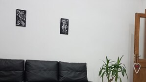 A black sectional sofa with a black and white striped rug, a potted plant, and two framed artworks on the wall. - Mary''s Sweet Home Appartamento Napoli (Naples)