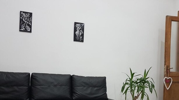A black sectional sofa with a black and white striped rug, a potted plant, and two framed artworks on the wall. - Mary''s Sweet Home Appartamento Napoli (Naples)