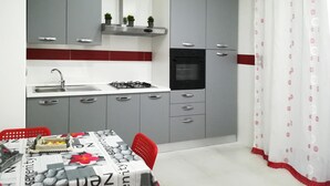 A modern kitchen with grey cabinets, a black oven, and a stainless steel sink. - Mary''s Sweet Home Appartamento Napoli (Naples)
