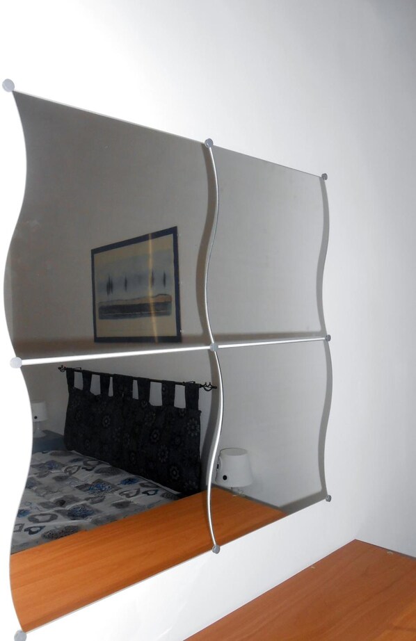 Une chambre avec un lit, une table de chevet, une lampe et un tableau encadré au mur.