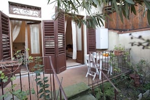 A courtyard with a table and chairs, a whiteboard, and a potted plant. - Flospirit - Bellini (Florence)