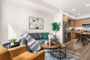 Ein modernes Wohnzimmer mit einer Couch, einem Sessel, einem Couchtisch und einem Bild an der Wand.