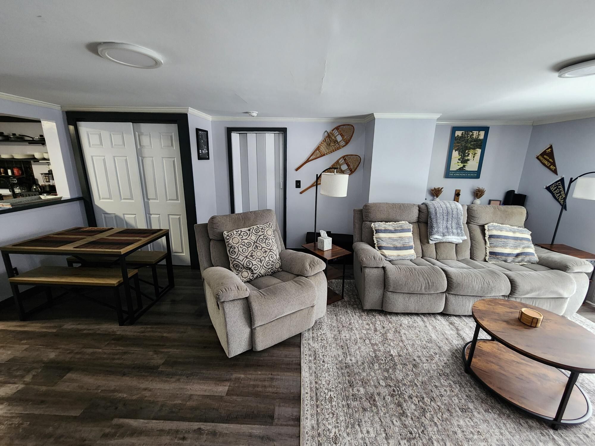 A living room with a sofa, armchairs, a coffee table, and a dining table.