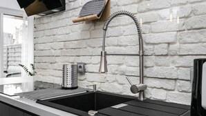 A modern kitchen with a stainless steel sink, a built-in grater, and a wooden shelf above the sink. - City Of The Kings Arianska Garden (Kraków)