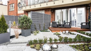 A modern residential building with a balcony, outdoor seating area, and a well-maintained garden. - City Of The Kings Arianska Garden (Kraków)