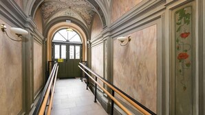 A hallway with a marble floor, a green door at the end, and a decorative ceiling. - City Of The Kings Arianska Garden (Kraków)