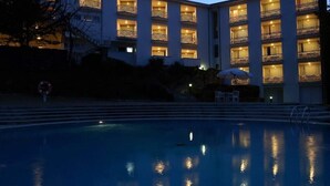 Un hôtel doté de nombreux balcons, d’une piscine et d’un espace extérieur aménagé pour s’asseoir.