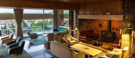 A spacious living room with a fireplace, comfortable seating, and a balcony with a view.