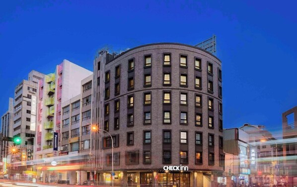 A multi-story building with a curved corner, featuring a Checkinn hotel sign at the ground level. - Double Pretty Hotel (Taichung)