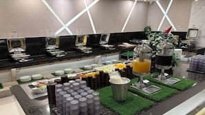 A buffet setup with various food items, a juice dispenser, and a coffee machine. - Double Pretty Hotel (Taichung)