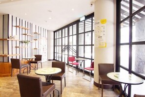 A spacious indoor area with multiple seating arrangements, including round tables and chairs, and large windows providing natural light. - Double Pretty Hotel (Taichung)