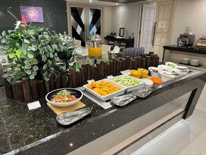 Ein Buffet mit verschiedenen Speisen, einer Kaffeemaschine und einer großen Pflanze.