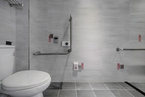 A modern bathroom with a toilet, grab bars, and a hand dryer. - H Inn (Taichung)