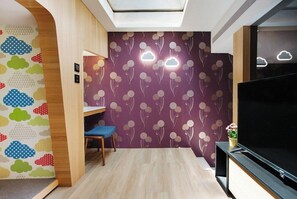 A modern living room with a TV, a blue chair, a wooden bench, and a ceiling light. - Petrichor Hotel (Taichung)