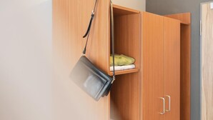 A wooden wardrobe with a hanging bag and folded clothes. - Garner Hotel Stuttgart - Zuffenhausen By IHG (Stuttgart)