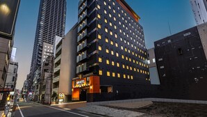 Een modern hotel met een donkere gevel, meerdere verdiepingen en verlichte ramen.