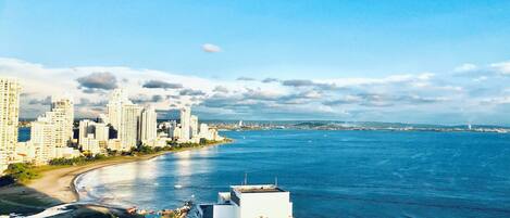 A high-rise hotel with a view of a coastal cityscape and the ocean.