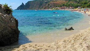 A beach with clear turquoise water, rocky cliffs, and a sandy shore. - La Torre del Mulino Accomodation (Tropea)