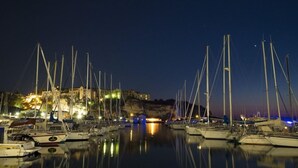 A marina at night with boats docked and a building in the background. - La Torre del Mulino Accomodation (Tropea)