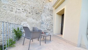 An outdoor seating area with a stone wall, a metal railing, and a door leading to a building. - La Torre del Mulino Accomodation (Tropea)