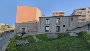 A modern building with a stone facade, a small garden with rocks and a pathway, and a staircase leading to an upper level. - La Torre del Mulino Accomodation (Tropea)