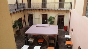 A courtyard with tables and chairs, a covered area, and a balcony with railings. - Hostel Marina (Cagliari)