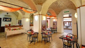 A dining area with tables and chairs, a buffet table with food, and a brick ceiling with arches. - Hostel Marina (Cagliari)