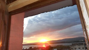 Une vue sur le coucher de soleil à travers une fenêtre, avec un mur de briques et des poutres en bois.