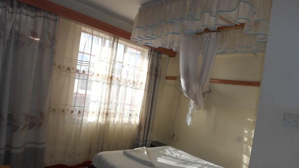 Een kamer met een bed, een stoel en gordijnen.